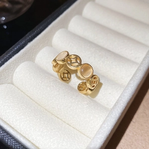 Detailed view of golden hollow coin ring with opal stone on beige velvet cushion