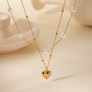Detail of a gold double-layer necklace with white pearls and polished heart pendant