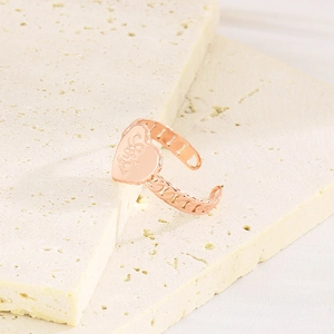 Détail d'une bague coeur en or rose avec gravure Love You et anneau en chaîne évidée