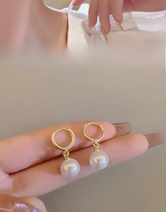 Detailed close-up of an elegant gold hoop earring with a polished white pearl drop