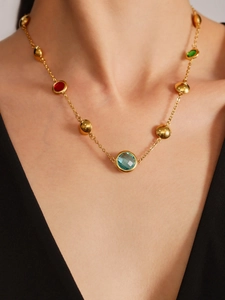 Elegant gold necklace with multi-colored glass gemstones and beads shown on a model