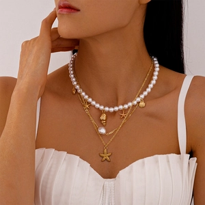 Dettaglio della collana multistrato a tema marino con ciondoli a stella marina e perle