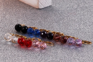 Macro shot of 10mm faceted crystal glass drop earrings in eight vibrant colors with gold hooks