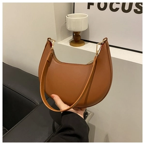Detailed view of the brown crescent bag's smooth leather texture and golden metal hardware