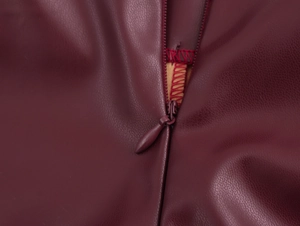 Detailed macro shot of burgundy PU leather texture with high-quality invisible zipper