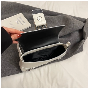 Detail view of the open white PU leather shoulder bag with magnetic silver buckle and black lining