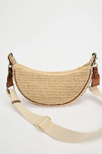 Detail of a beige woven half-moon bag with brown leather trim and golden hardware