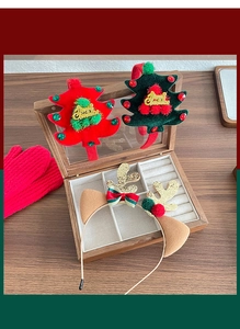 Detailed view of plush Christmas headbands with glitter trees and reindeer antlers in a box