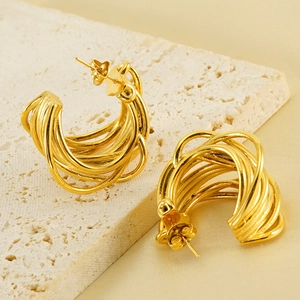 Modern 18K gold-plated C-shaped layered hoop earrings on a textured stone background