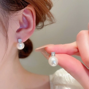 Détail de boucles d'oreilles perles avec papillon en zircone sur un modèle féminin