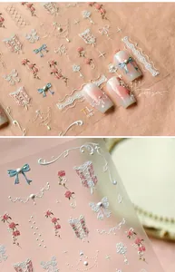 Detailed macro view of 3D embossed nail stickers with pink roses and blue bows