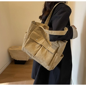 Detail of khaki corduroy tote bag showing ribbed texture and front utility pockets