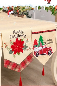 Detail of Christmas table runner with red tassels and truck with gnome embroidery