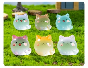 Macro shot of colorful luminous cat figurines on a green miniature lawn landscape