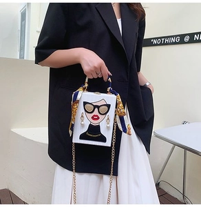 Detail of white box clutch bag featuring cartoon fashion girl illustration and scarf handle