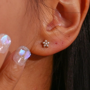 Gros plan d'une boucle d'oreille fleur miniature plaquée or 18 carats avec perles