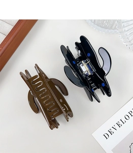 Detail view of brown and black acetate hair claws with a smooth glossy finish on a desk