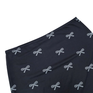 Detail of black mini skirt with white bow print patterns and smooth fabric texture