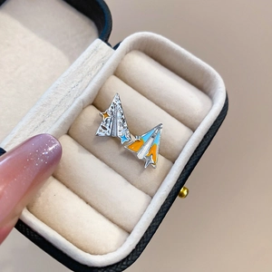 Détail des boucles d'oreilles avion en émail coloré dans un coffret cadeau en velours
