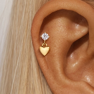 Detailed view of a gold S925 silver heart dangle earring with cubic zirconia on an ear
