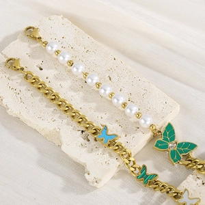 Detailed shot of vintage gold bracelet with green butterfly charms and white pearls