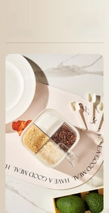 Detail showing four-grid transparent spice box with small spoons on marble surface