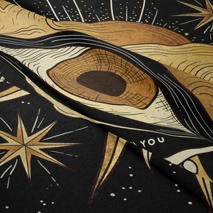 Detail of soft black velvet fabric with gold sun and celestial eye mystical pattern