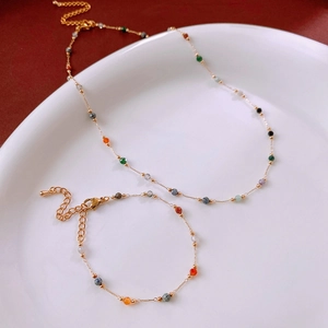 Detailed flat lay of golden necklace and bracelet set with colorful round beads
