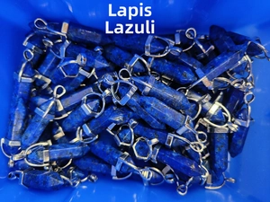 Bulk lot of hexagonal lapis lazuli pendants with silver metal clasps in a blue container