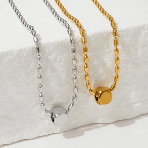 Minimalist gold and silver oval bead necklaces displayed on a textured stone surface