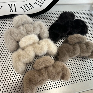 Flat lay of five plush claw clips in grey, beige, black, and brown on a metal board