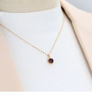 Detail of round purple agate pendant on a gold titanium steel chain for women