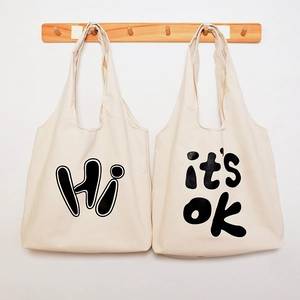 Canvas tote bag detail view showing natural fabric texture and black stylish letter prints.