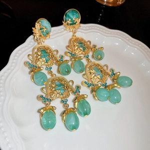 Détail de boucle d'oreille rétro dorée avec perles en résine verte et strass bleus