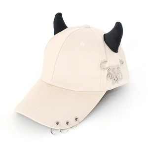 Detail of beige punk baseball cap featuring black devil horns and silver metal rings