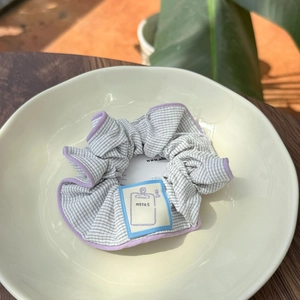Macro view of a striped scrunchie with blue fabric label and purple piping detail