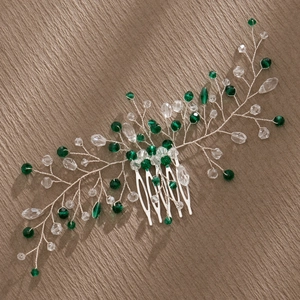 Close-up of handmade bridal hair comb with silver wire branches and green crystal beads