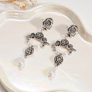 Detail of vintage silver rose earrings with elegant white teardrop pearl drops