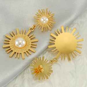 Elegant 18k gold plated sun flower drop earrings with white pearls on satin background