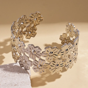 Close-up of silver hollowed flower pattern on layered metal open cuff bracelet