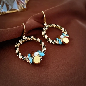 Detailed shot of vintage gold drop earrings with colorful beads on brown satin fabric