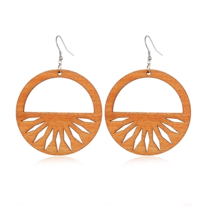 Macro detail of geometric hollow wood earrings with a radial cutout design and metal hooks