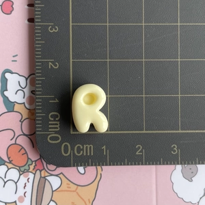Mini yellow resin letter R accessory showing 1.5cm size on a professional scale mat