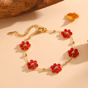 Detail of a gold stainless steel bracelet featuring red flower charms and lobster clasp