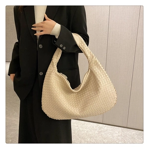 Detail of a large beige woven leather hobo tote bag showcasing intricate texture and craftsmanship