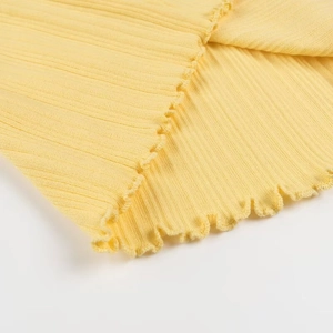 Détail macro du tissu en maille côtelée jaune avec des finitions délicates à volants