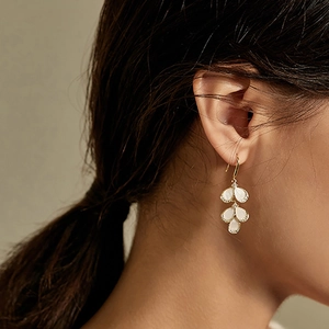 Detailed close-up of leaf-shaped cat-eye stone earrings with zirconia on female model