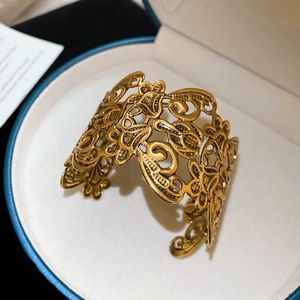 Detailed view of wide gold cuff bracelet featuring intricate floral cut-out patterns