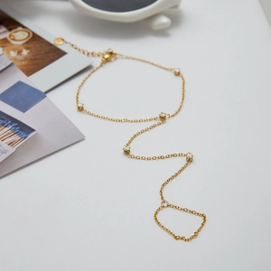 Close-up of golden hand chain with zircon stones on a stylish white background