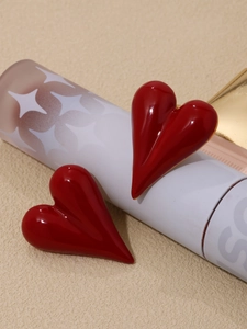 Detailed view of red glossy heart studs with a vintage enamel finish on a white stand